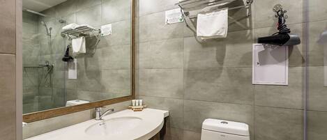 A modern bathroom with a large mirror, a sink, a toilet, and a shower area.