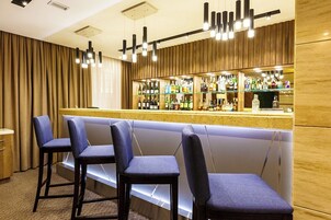 Zona de bar con pared de madera, una barra y tres taburetes azules.