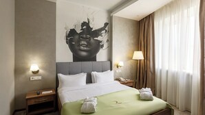 Ein Hotelzimmer mit einem großen Bett, zwei Nachttischen, einer Wandlampe und einem großen Fenster mit Vorhängen.