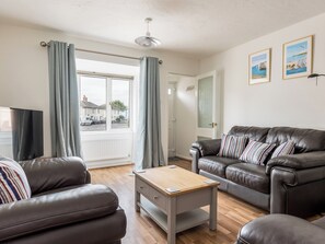 A living room with a leather sofa, a wooden coffee table, and a television. - 3 bedroom accommodation in Poole (Poole)