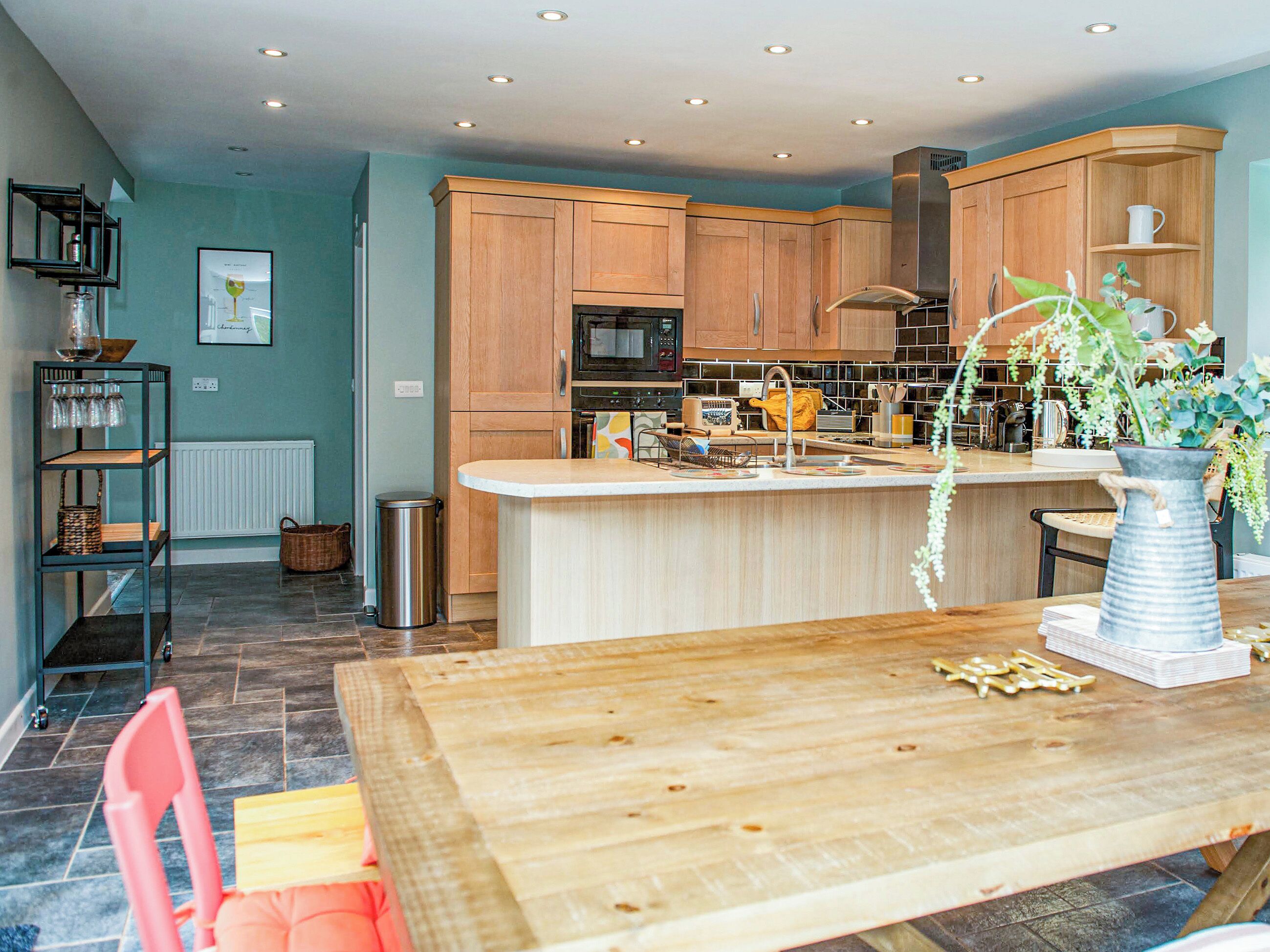 A modern kitchen with wooden cabinets, a central island, and a dining area with a wooden table and chairs.
