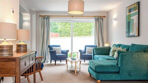 A living room with a sofa, two armchairs, a coffee table, and a desk with lamps. - 4 bedroom accommodation in Uplyme (Uplyme)