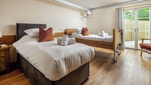 Hotelkamer met twee bedden, houten vloer, een klein bureau en uitzicht op het buiten via een schuifdeur.