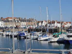 A marina with multiple boats docked, surrounded by buildings with red roofs. - Durham Lodge - UKC5799 (Lundin Links)