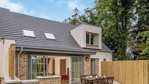 Een modern huis met een terras, een eethoek en een groot raam.