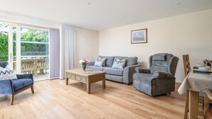 Una sala de estar con sofá, sillón, mesa de centro y mesa de comedor con sillas.