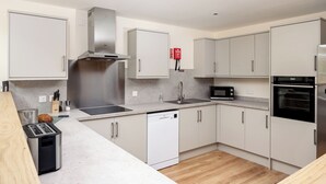 A modern kitchen with stainless steel appliances, white cabinetry, and a wooden countertop. - Largo Lodge - UKC5801 (Lundin Links)