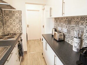 A kitchen with patterned tiles, a stove, a toaster, and a marble container.