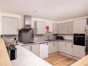 A modern kitchen with stainless steel appliances, white cabinets, and a wooden countertop. - Lundin Lodge - UKC5802 (Lundin Links)