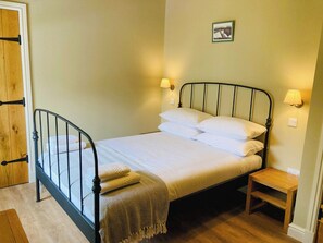 A single bed with a metal frame, white bedding, and two bedside lamps.