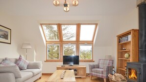 Ein gemütliches Wohnzimmer mit einer Couch, einem Holztisch, einem Fernseher, einem Kamin und einem Bücherregal.