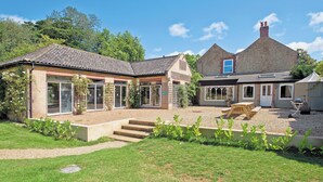Ein zweistöckiges Haus mit überdachter Terrasse, Vorgarten und Kiesweg.