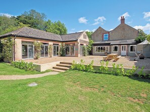 Ein zweistöckiges Haus mit überdachter Terrasse, Vorgarten und Kiesweg.