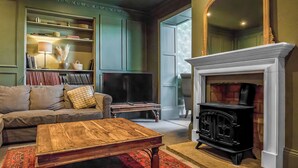 Ein Wohnzimmer mit Kamin, einer Couch, einem Couchtisch und einem Bücherregal.