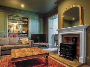 A living room with a fireplace, a sofa, a coffee table, and a bookshelf. - 7 bedroom accommodation in Sedgeford, near Hunstanton (Sedgeford, near Hunstanton)