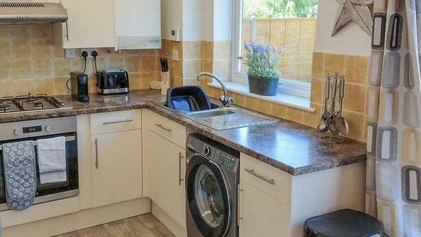 Une cuisine de taille réduite équipée d’un lave-linge, d’un grille-pain et d’un évier.