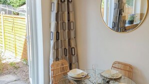 Un coin repas avec une table en verre, des chaises en osier et un miroir au mur.