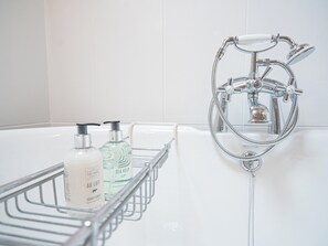 Ein Badezimmer mit einer Badewanne, einer Dusche und einem Ablagefach für Toilettenartikel.
