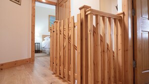Una scala in legno con ringhiera che conduce a una camera da letto.