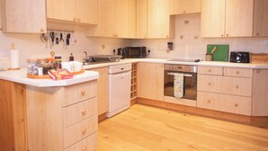 Una cucina con mobili in legno, lavastoviglie, forno e microonde.