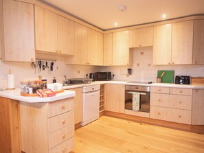 A kitchen with wooden cabinets, a dishwasher, an oven, and a microwave. - Steading Cottage - UKC5957 (Port Appin)