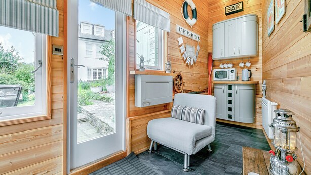Een gezellig chaletinterieur met houten details, een zithoekje, een kitchenette en uitzicht op de omgeving.