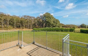 A fenced outdoor area with a clear view of a grassy field and trees. - 4 bedroom accommodation in Thorpeness (Thorpeness)