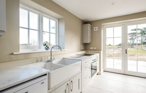 A modern kitchen with a large window, a built-in oven, and a sink. - 4 bedroom accommodation in Thorpeness (Thorpeness)
