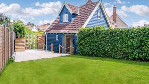 A two-story house with a blue exterior, a tiled roof, and a wooden deck leading to a door. - A romantic bolt hole near famous Aldeburgh on the Suffolk Heritage Coast. (Aldringham)