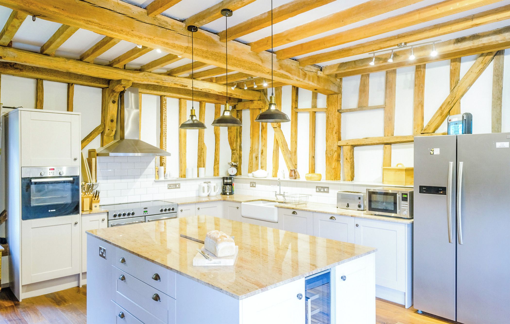 A kitchen with wooden beams, a central island, and modern appliances.