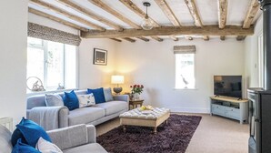 A living room with a sofa, ottoman, and a television. - 2 bedroom accommodation in Blyford, near Halesworth (Blyford, near Halesworth)