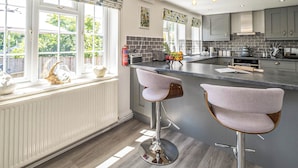 A modern kitchen with a large island, bar stools, and a view of the outdoors. - 2 bedroom accommodation in Blyford, near Halesworth (Blyford, near Halesworth)