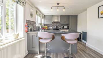 A modern kitchen with grey cabinets, a central island with bar stools, and a window with a view of greenery.