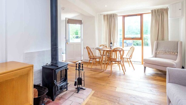 Una sala de estar acogedora con una estufa de leña, un comedor con sillas de madera y un sofá.