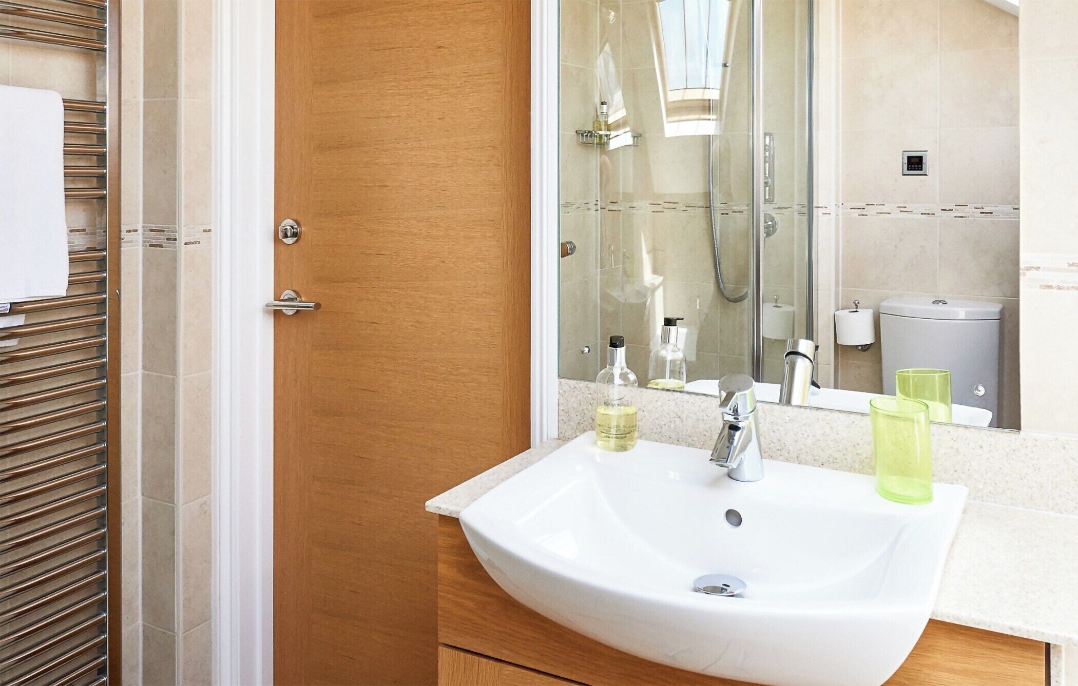 Une salle de bain avec un lavabo blanc, une cabine de douche en verre et une porte en bois.