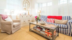 A living room with striped furniture, a coffee table with magazines, and a decorative mirror. - 2 bedroom accommodation in Aldeburgh (Aldeburgh)