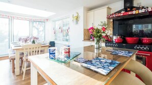 A modern kitchen with a central island, red cooking pots, and a decorative backsplash. - 2 bedroom accommodation in Aldeburgh (Aldeburgh)