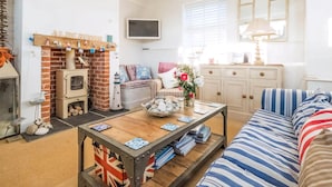 A cozy living room with a fireplace, a television, a sofa, and a coffee table. - 2 bedroom accommodation in Aldeburgh (Aldeburgh)