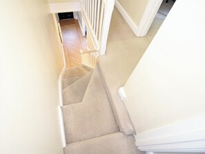 A carpeted staircase with white railings leading to a room with a wooden floor. - A fabulous Victorian terraced cottage set right in the heart of Borth Y Guest. (Borth Y Guest, Near Porthmadog)