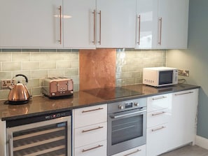 Eine Küche mit weißen Schränken, einem Edelstahlbackofen, einer Mikrowelle, einem Toaster und einem Wasserkocher.
