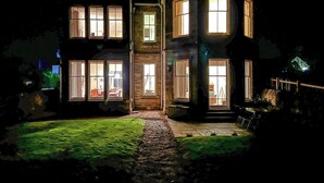 Una casa de dos pisos amb diverses finestres il·luminades a la nit.