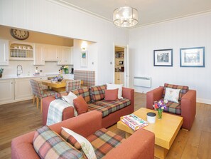 A cozy living room with a sofa set, a coffee table, and a dining area with a table and chairs. - 3 bedroom accommodation in St Andrews (St Andrews)