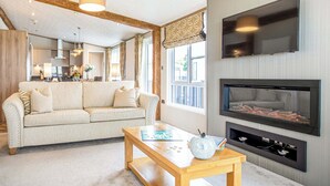 Una sala de estar con sofá, mesa de centro, chimenea y televisor montado en la pared.