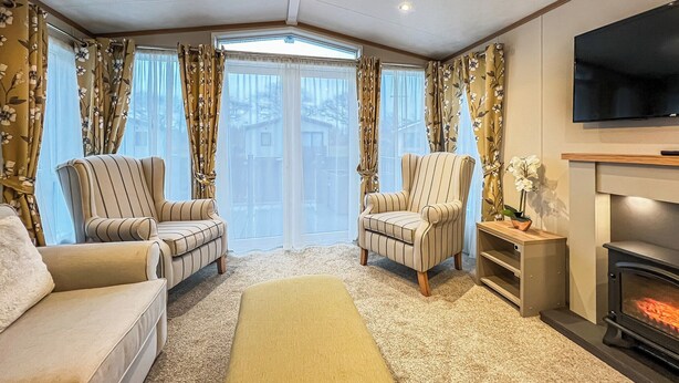 A cozy living room with two striped armchairs, a sofa, a large window with curtains, a fireplace, and a television. - Cute, cosy and warm. (St Andrews)