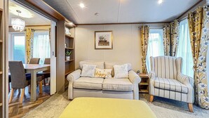 A cozy living room with a sofa, armchair, and ottoman, a dining area with a table and chairs, and a bookshelf. - Cute, cosy and warm. (St Andrews)