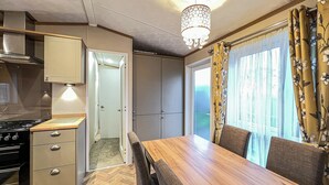 A compact kitchen with a stove, cabinets, and a dining area with a table and chairs. - Cute, cosy and warm. (St Andrews)