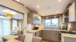 A compact kitchen with a dining area, a window with blinds, and a radiator. - Cute, cosy and warm. (St Andrews)