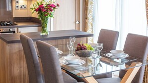 Ett modernt kök med en köksö i mitten, en matplats med ett glasbord och en vas med blommor.