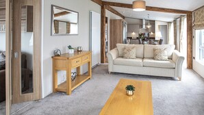 Ett vardagsrum med ett soffbord i trä, en beige soffa och ett konsolbord i trä med lådor.