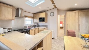 Una cucina compatta con mobili in legno, un forno a microonde integrato, un piano cottura e un lucernario.